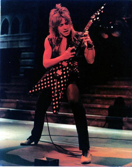 Black and white publicity shot of Randy Rhoads playing his Polka Dot Flying V guitar on stage