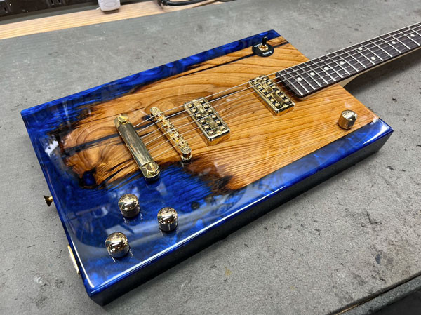 Close-up of the completed guitar, highlighting the control knobs and bridge hardware, showcasing the finished craftsmanship.