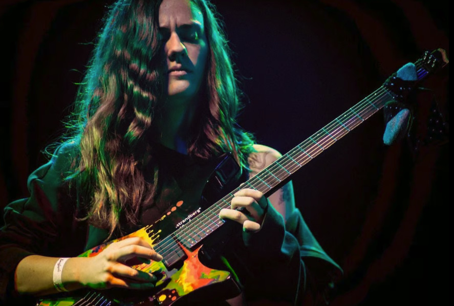 Screenshot of a hand playing a Strandberg guitar, demonstrating comfortable reach and ergonomic design for complex 7-string chord shapes.