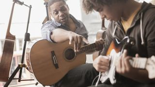 Man teaching guitar to a woman