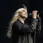 Taylor Momsen of The Pretty Reckless performing live, bathed in stage lights.
