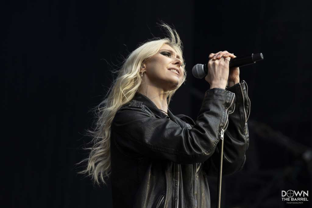 Taylor Momsen of The Pretty Reckless performing live, bathed in stage lights.