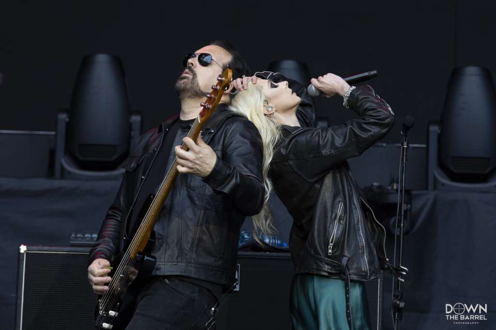 Ben Phillips of The Pretty Reckless playing guitar with stage lights illuminating him.