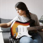 Lady playing guitar at laptop