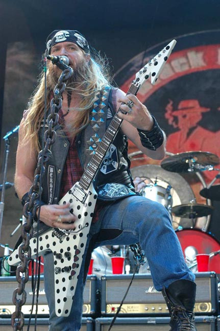 Zakk Wylde playing a white and black reverse polka dot GMW Flying V guitar on stage