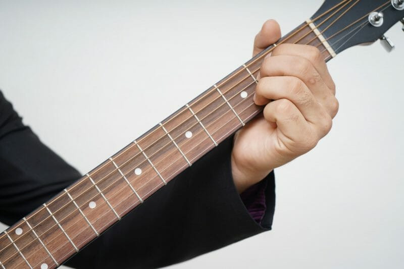 An acoustic guitar resting against a wall, symbolizing dedicated practice