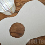 Cardboard guitar body ready for assembly, showcasing the cut-out shape and sound hole