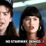 Wayne Campbell looking at the NO STAIRWAY TO HEAVEN sign in Wayne's World