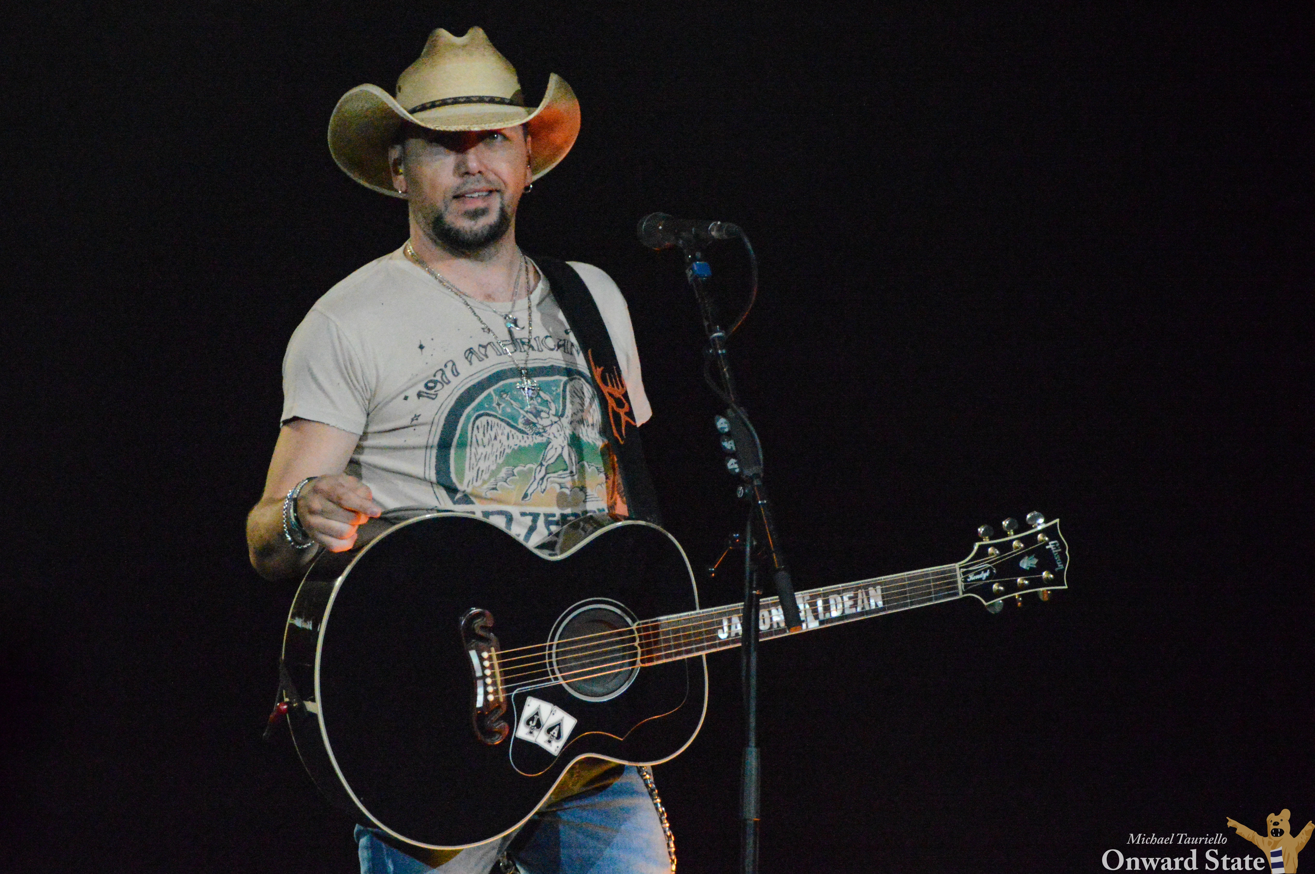 Jason Aldean bathed in green lights, the crowd cheering during the &quot;Big Green Tractor&quot; performance at the Bryce Jordan Center, capturing the song's lively energy.
