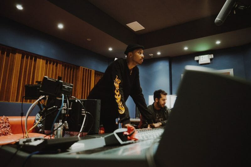 A music producer in a recording studio, brainstorming ideas while holding a guitar