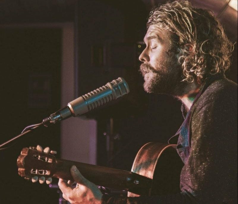 A singer-songwriter pouring their heart into a song while playing guitar