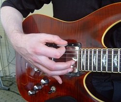 Pinky finger rested on guitar body near pickup switch