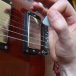 Fret hand rested on guitar bridge for stability