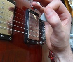 Fret hand rested on guitar bridge for stability